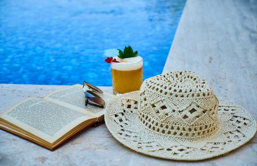 šešir i knjiga pored bazena